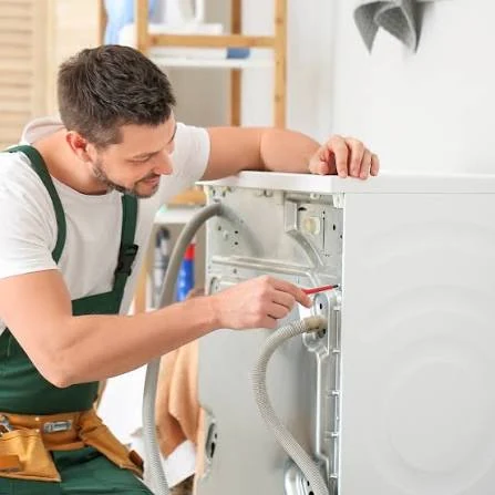 Technician checking hoses and connections behind a laundry appliance