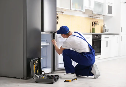 Technician inspecting an open refrigerator in a bright kitchen