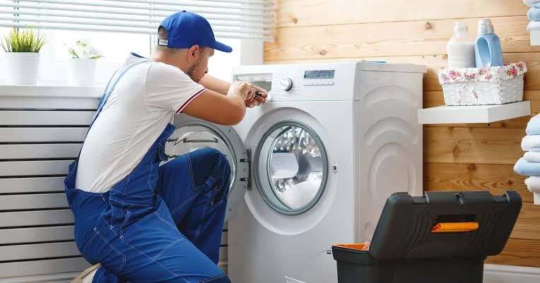 Technician inspecting the controls of a washing machine in a laundry room